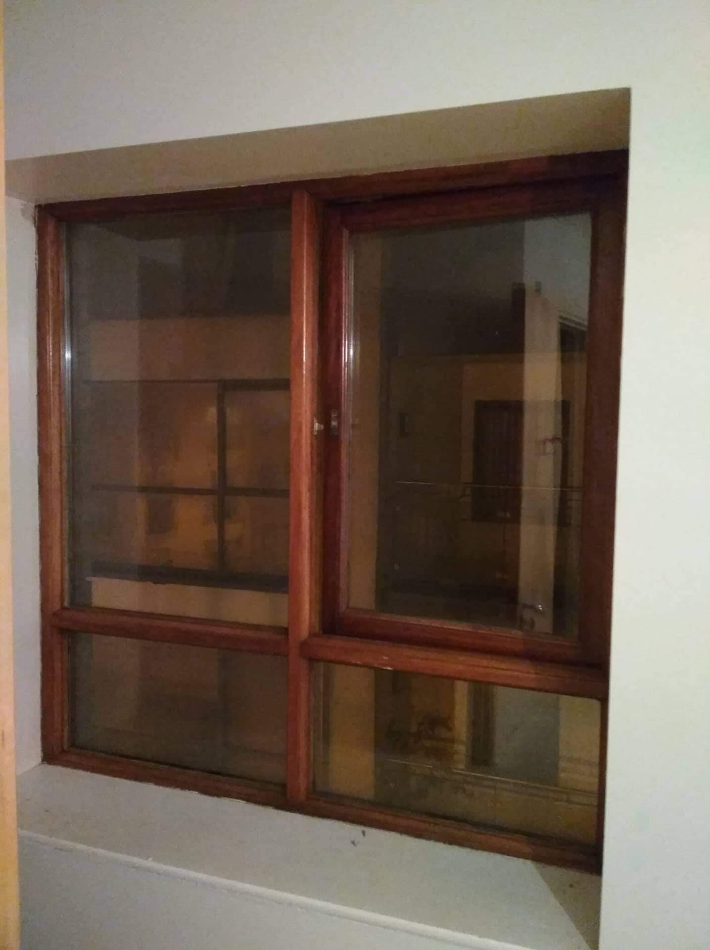 Okna drewniane z widocznym refleksem wnętrza, osadzone w białej ścianie.