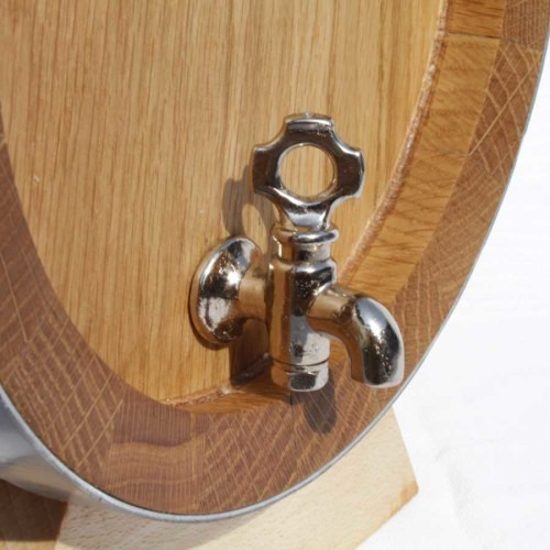 Dębowa beczka z chromowanym kranem, widoczne detale słojów drewna i metalowe okucie.