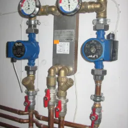 Kompleksowa instalacja grzewcza z dwoma pompami obiegowymi LFP Leszno, manometrami wskazującymi ciśnienie i temperaturę, zaworami z czerwonymi uchwytami oraz miedzianymi rurami, zamontowana...