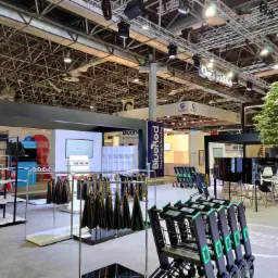 Wnętrze stoiska targowego z ekspozycją wózków sklepowych z wyświetlaczami, regałami i elementami identyfikacji wizualnej firmy.