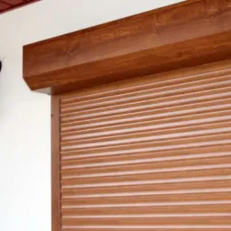 Zewnętrzna brama rolowana w kolorze drewna, zamontowana przy białej ścianie z czarną lampą w stylu retro.