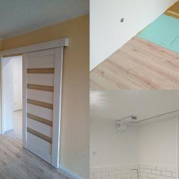 irko tech - Pokój po remoncie z przesuwnymi drzwiami i nową podłogą, widoczna również instalacja wentylacyjna pod sufitem w łazience wykończonej białymi płytkami.