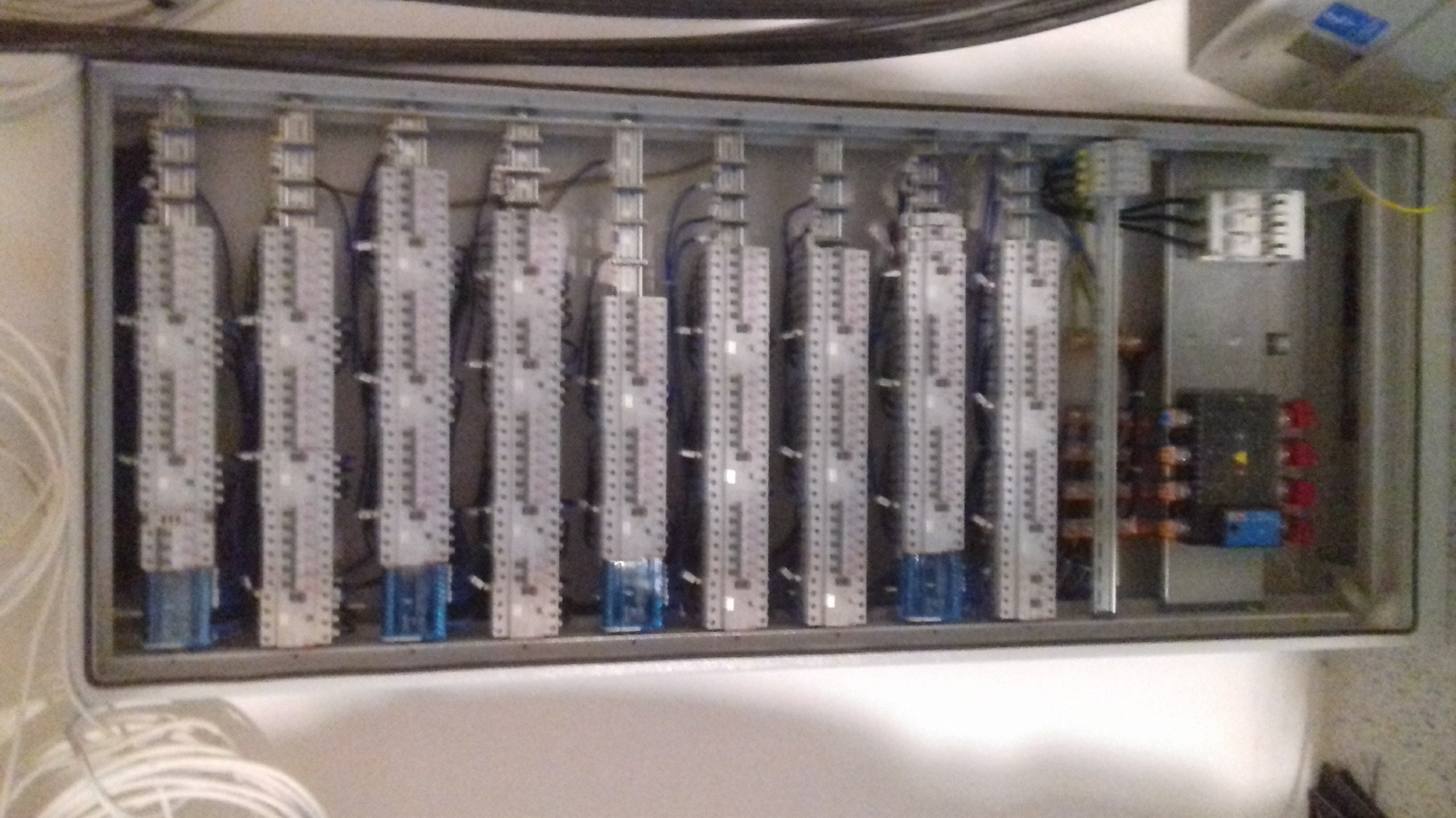 Rozdzielnica elektryczna z listwami zaciskowymi, widoczne przewody i elementy sterujące w metalowej obudowie.