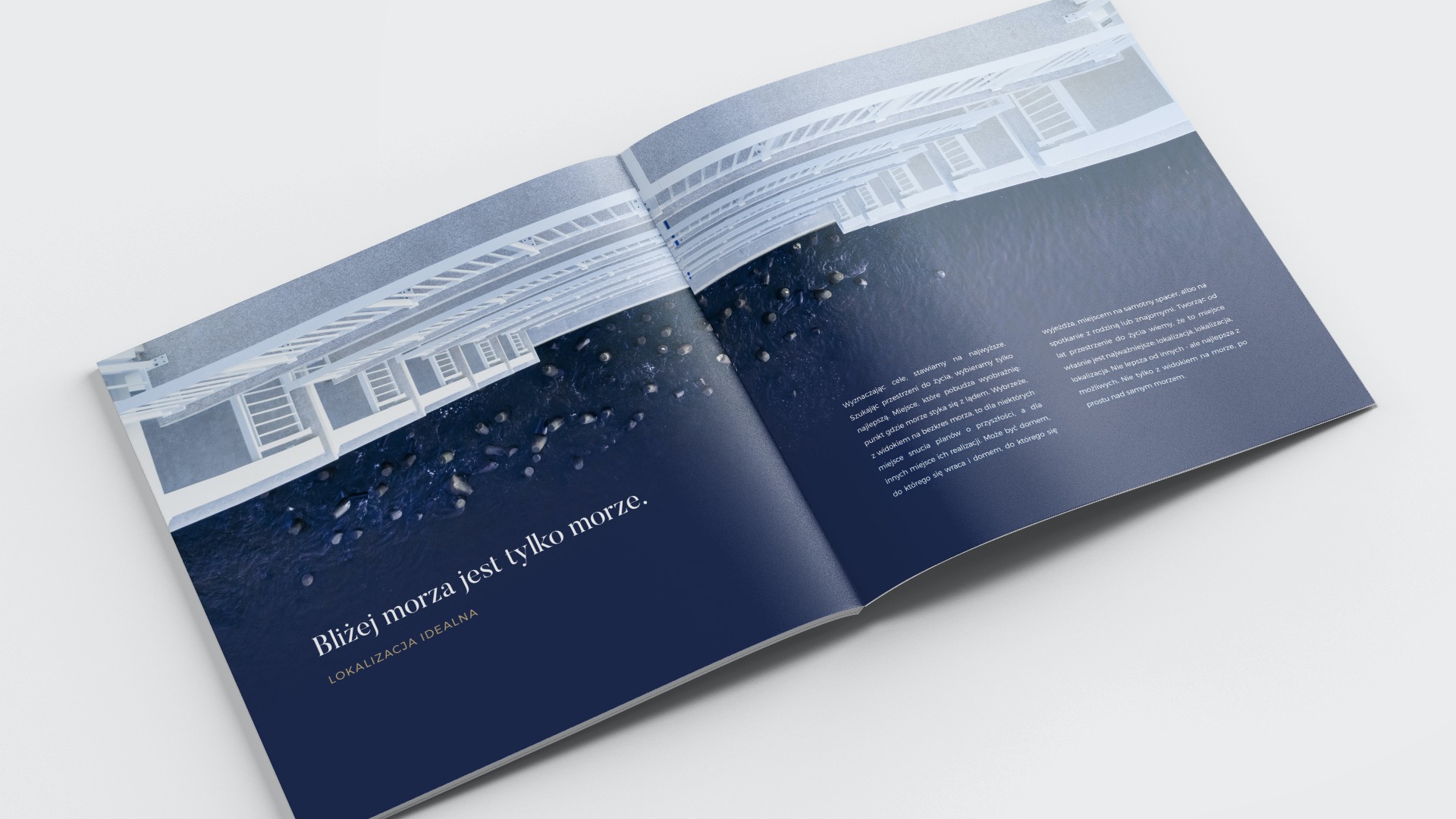 Otwarta broszura reklamowa z widokiem na morze z balkonu, tekst 'Bliżej morza jest tylko morze' i 'Lokalizacja idealna' na stronie po lewej, opis lokalizacji na stronie po prawej.