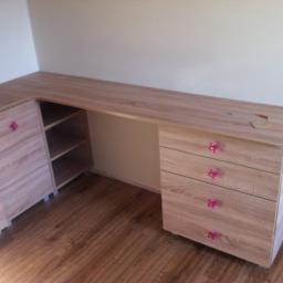 Meble Pod Wymiar - Biurko narożne na wymiar z jasnego drewna z szufladami i półkami, wykończone różowymi uchwytami w kształcie kwiatów, na blacie leżą kredki.