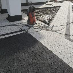 F.P.H.U Dan-Bud - Ułożona dwukolorowa kostka brukowa przed budynkiem, z widocznym odpływem liniowym, myjką ciśnieniową i fragmentem terenu przygotowanego pod dalsze prace.