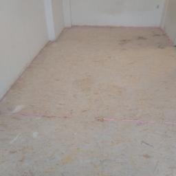 J.P. Kompleksowe Usługi Remontowe - Przygotowanie podłoża pod podłogę: płyty OSB na podłodze z różową pianką montażową przy ścianach, surowy stan, widoczne łączenia płyt.