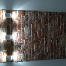 Dekoracyjna ściana z czerwonej cegły z trzema białymi, cylindrycznymi lampami ściennymi, oświetlającymi nierówną fakturę cegieł i fug.