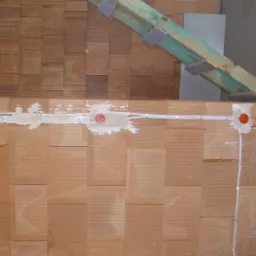 Ściana z cegły ceramicznej z widocznymi przewodami elektrycznymi w białej izolacji, zamocowanymi klamrami i osadzonymi puszkami instalacyjnymi w zaprawie gipsowej, fragment konstrukcji drewnianej...