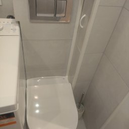 P.H.U. REMONT Andrzej Staniszewski - Kompaktowa toaleta wisząca z przyciskiem spłukującym w chromowanej ramce, obok pralka w minimalistycznej łazience wykończonej szarymi płytkami.