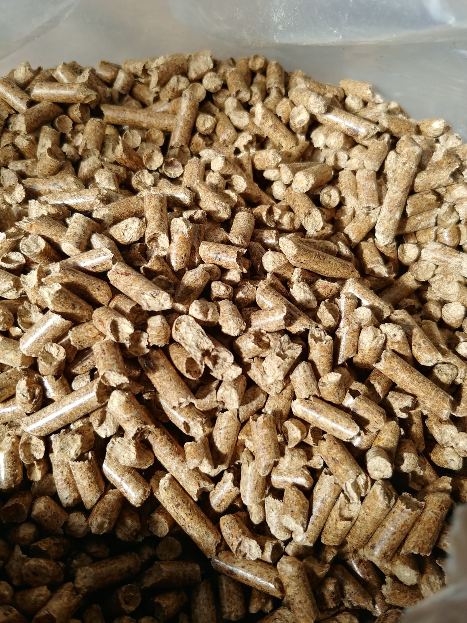 Napełniony worek z granulatem z biomasy, widoczne nierównomierne bryłki i włókna drzewne.