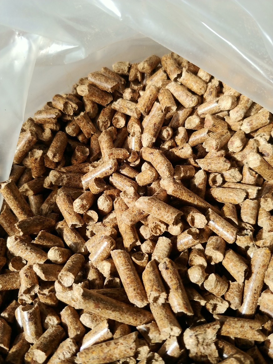 Jasnobrązowe granulki opału w przezroczystym worku, widoczne drobne nierówności i struktura drewna.