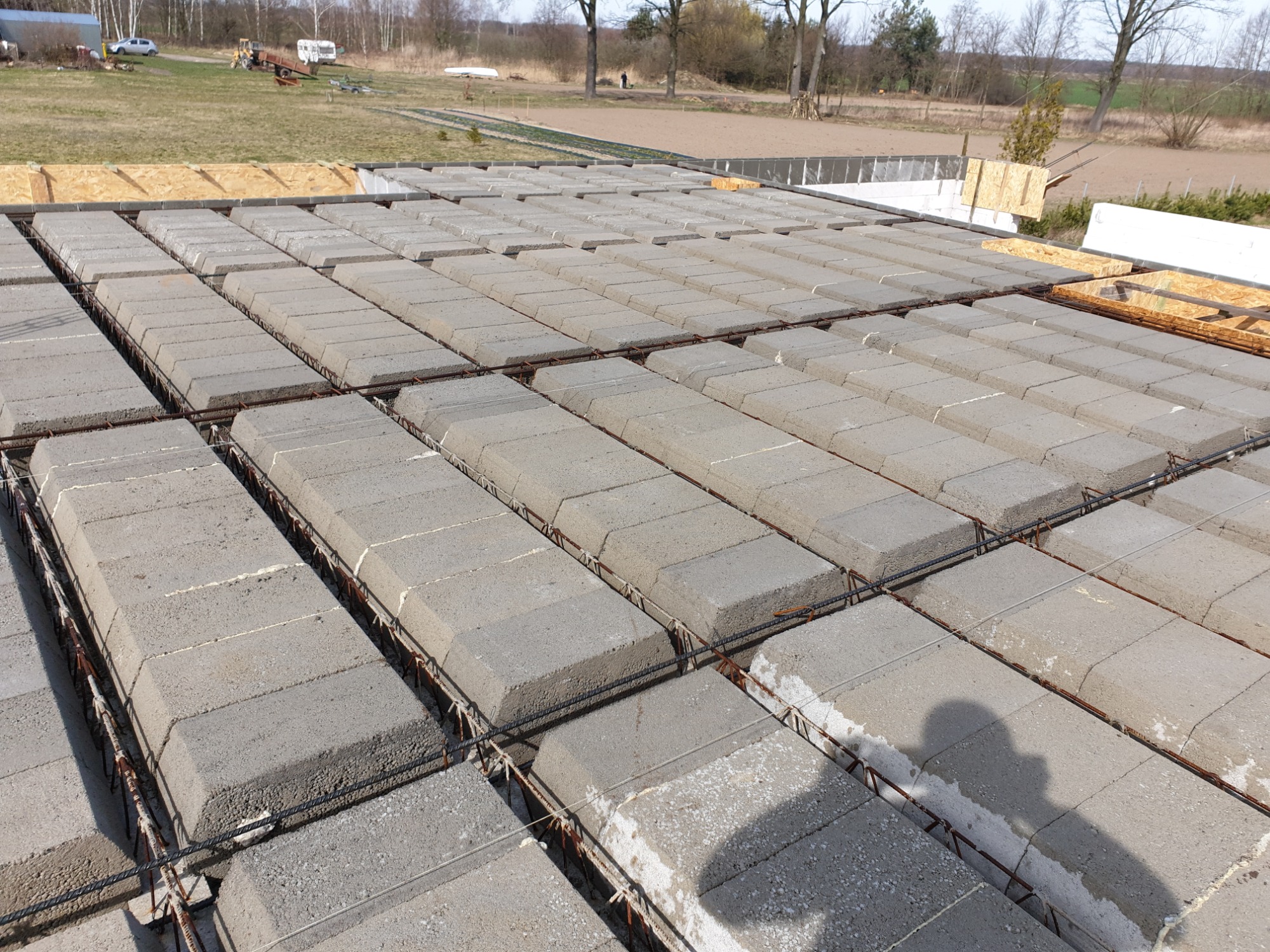 Wypełniony strop Teriva z widoczną siatką zbrojeniową i elementami szalunku w tle.