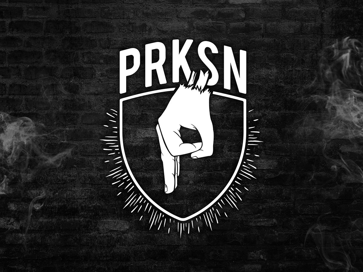 Białe logo PRKSN z dłonią wewnątrz tarczy na tle czarnej ściany z cegieł i dymu.