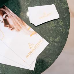 Avenue Estetic Klinika Kosmetologii - Ulotki i wizytówki z logo 'Avenue Estetic Klinika Kosmetologii' leżące na zielonym marmurowym stoliku.