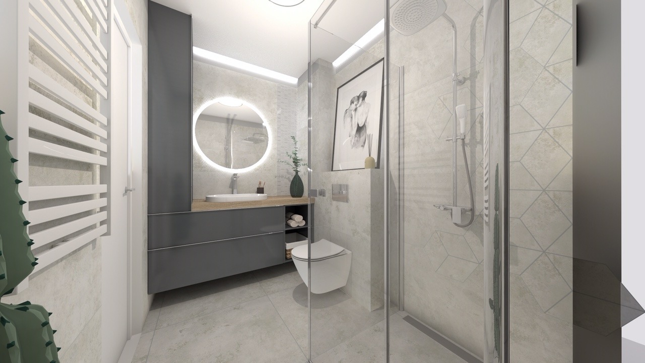 Nowoczesna łazienka z okrągłym lustrem podświetlanym LED, szarą szafką pod umywalką z drewnianym blatem, kabiną prysznicową ze szklanymi drzwiami i toaletą podwieszaną, całość utrzymana w jasnej...