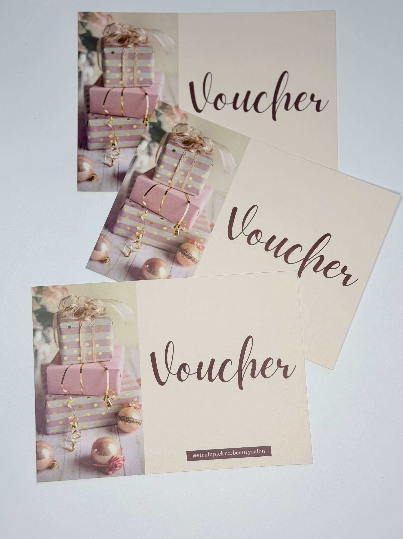 Trzy vouchery na beżowym tle z motywem prezentów w odcieniach różu i złota oraz napisem 'Voucher' w kolorze brązowym, jeden z nich zawiera dodatkowo adres profilu salonu kosmetycznego.