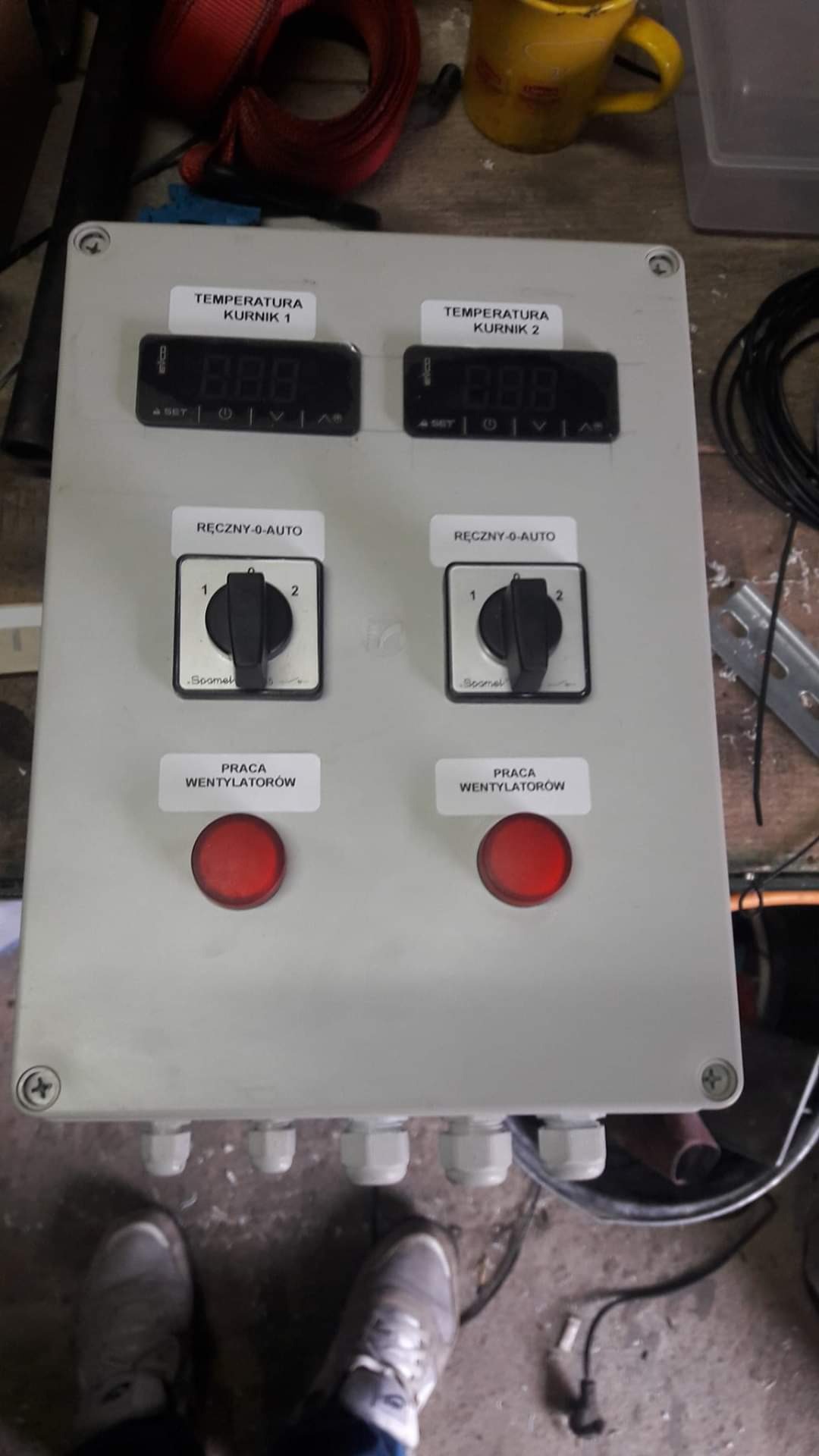 Panel sterowania z dwoma wyświetlaczami temperatury, przełącznikami trybu pracy (ręczny/auto) i czerwonymi przyciskami sygnalizującymi pracę wentylatorów, prawdopodobnie do kontroli klimatu...