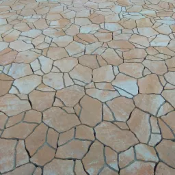 Powierzchnia wyłożona nieregularnymi, beżowo-pomarańczowymi płytami kamiennymi, tworzącymi mozaikę z szarymi spoinami.