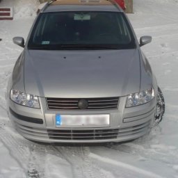 Usługi Blacharsko-Lakiernicze oraz motoryzacyjne - Przód srebrnego samochodu osobowego marki Fiat Stilo stojącego na śniegu w zimowy dzień.