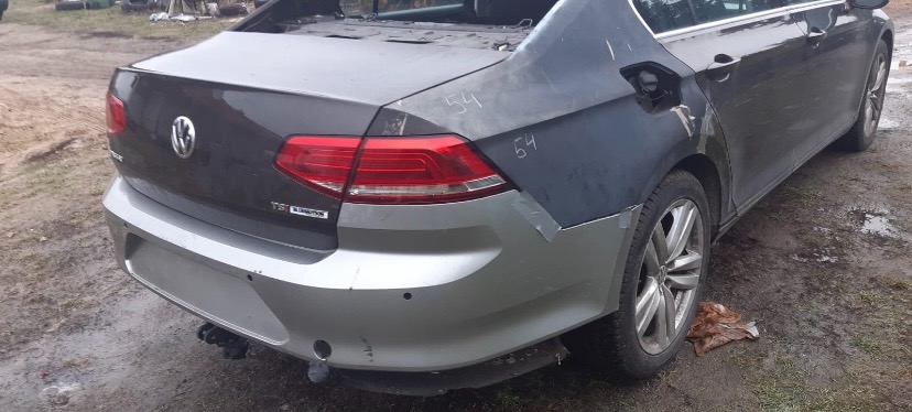 Fragment naprawianego samochodu Volkswagen Passat z widocznymi elementami karoserii przygotowanymi do lakierowania, zabezpieczonymi taśmą i z naniesionymi oznaczeniami.