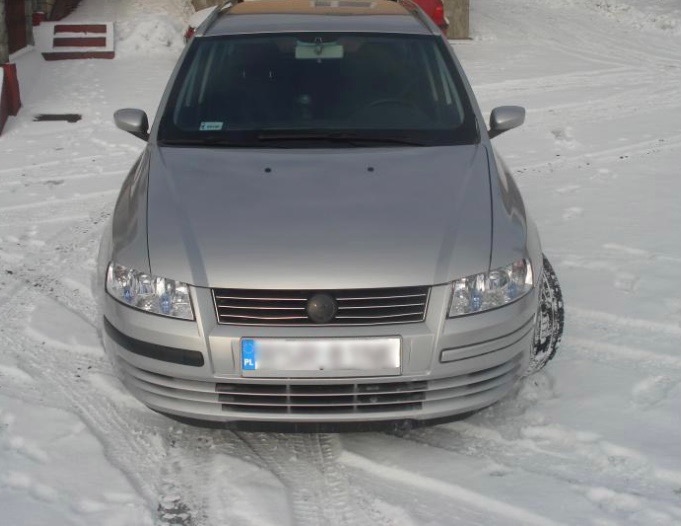 Przód srebrnego samochodu osobowego marki Fiat Stilo stojącego na śniegu w zimowy dzień.