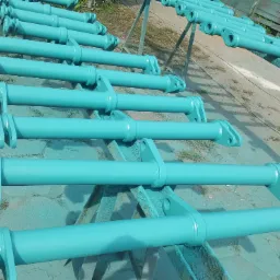 Turkusowe, pomalowane elementy konstrukcyjne z uchwytami, ułożone rzędami na metalowym stojaku po malowaniu.