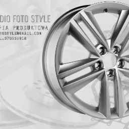 Aluminiowa felga samochodowa na tle części samochodowych z logo studia fotograficznego.