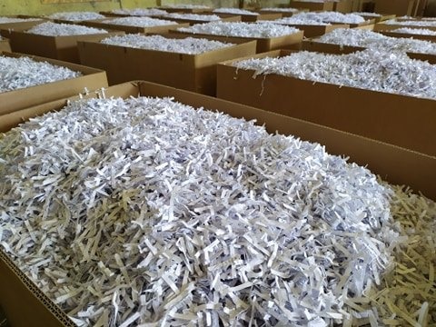 Kartonowe pudła wypełnione pociętymi dokumentami w Krakowie, gotowe do utylizacji.