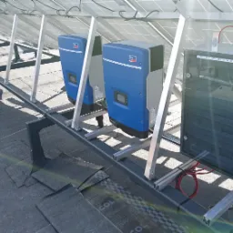 Instalacja fotowoltaiczna na dachu w Nowym Sączu, widoczne dwa niebieskie inwertery SMA oraz rozdzielnica AC/DC zamontowane na aluminiowej konstrukcji wsporczej.