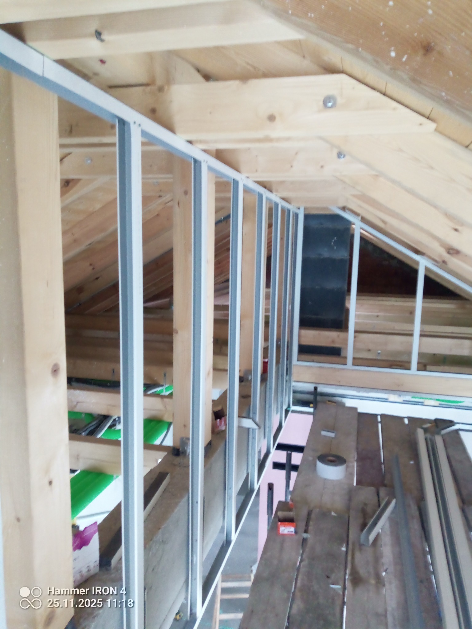 Montaż metalowej konstrukcji szkieletowej na drewnianym poddaszu, widoczne profile i elementy mocujące. Prace przygotowawcze do dalszych etapów wykończenia.