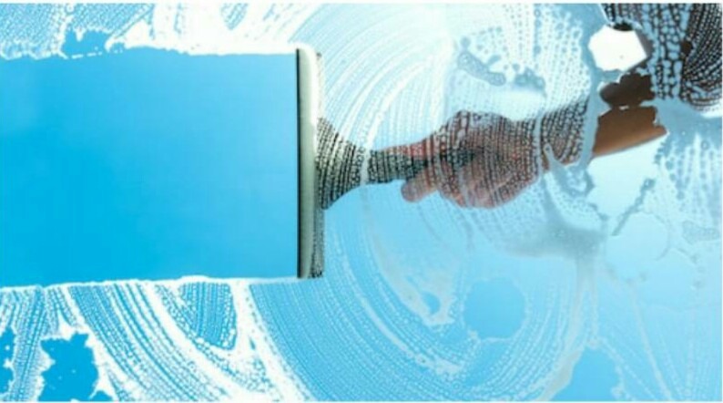 Mycie okna z zewnątrz za pomocą ściągaczki, widoczne smugi piany i odbicie nieba.