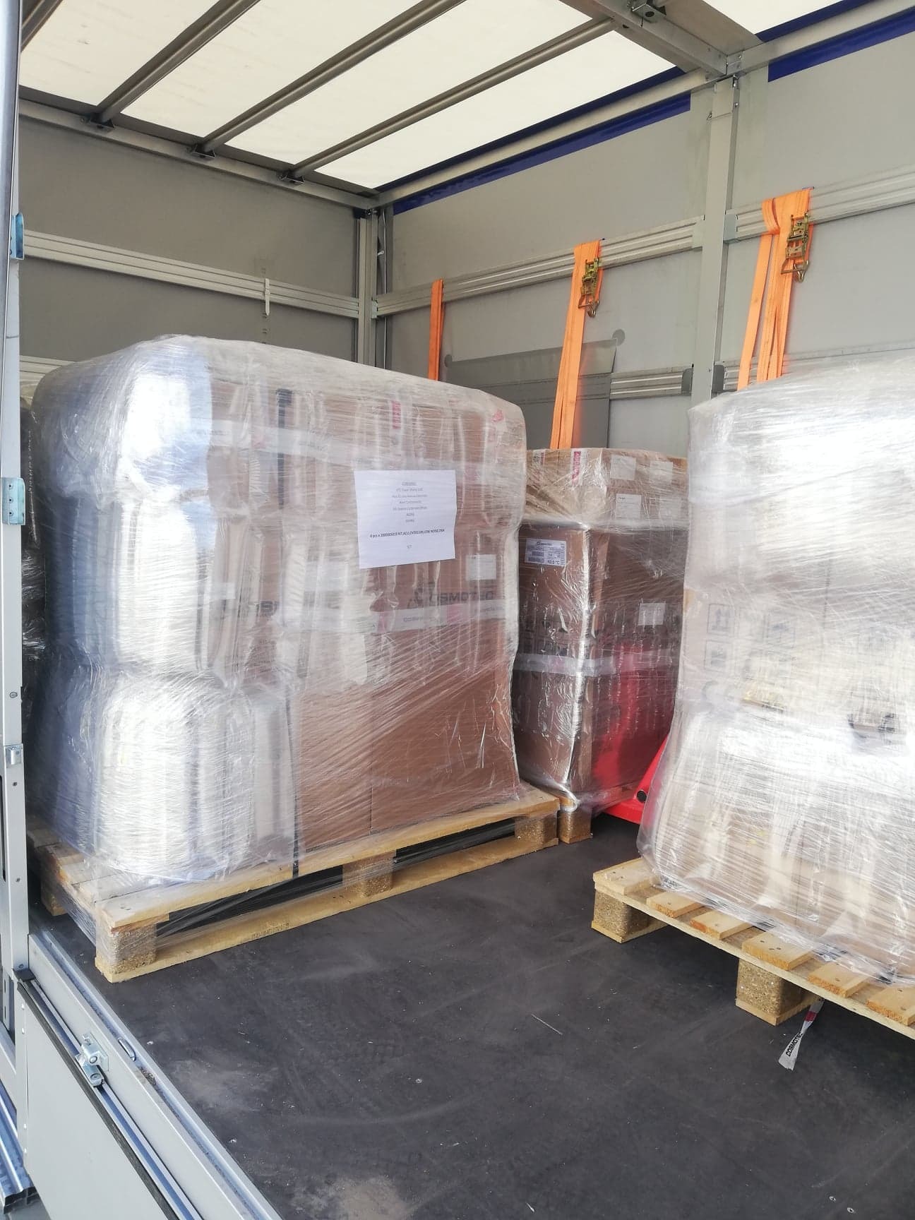 Wnętrze przestrzeni ładunkowej z paletami owiniętymi folią stretch, zabezpieczonymi pomarańczowymi pasami mocującymi.