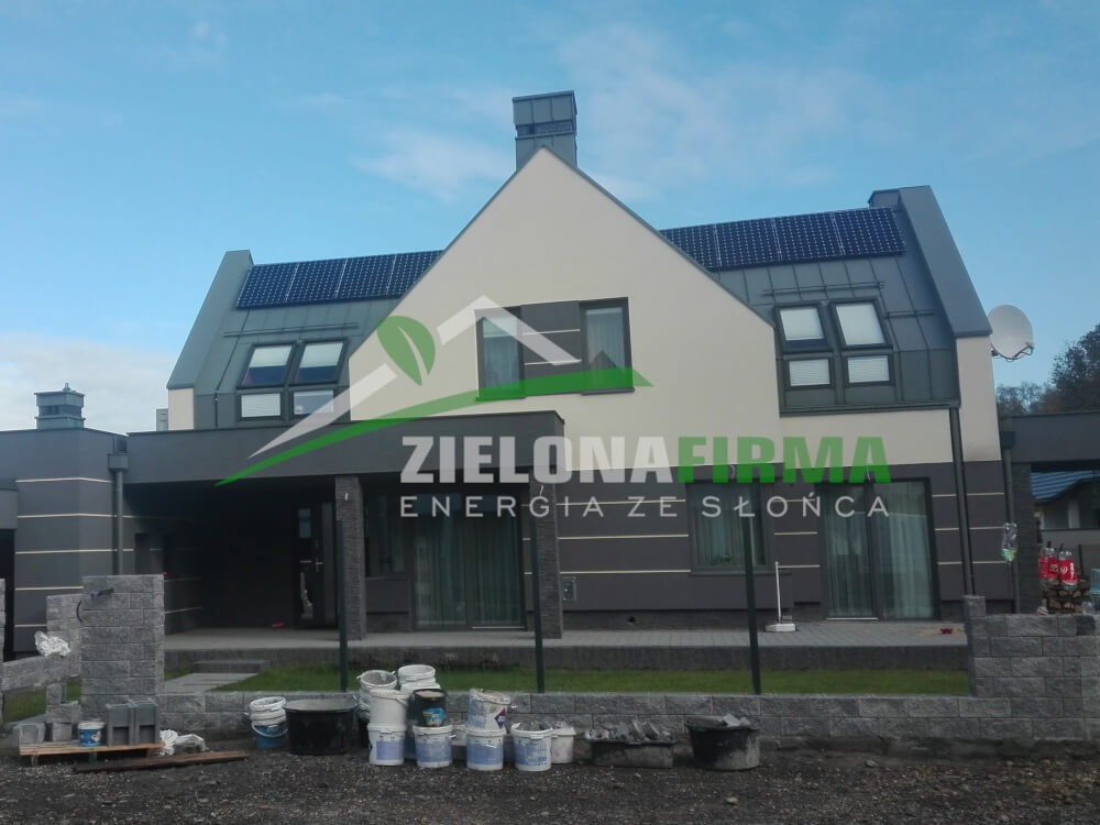 Dom jednorodzinny w Połańcu z panelami słonecznymi na dachu, zamontowanymi przez Zieloną Firmę. Widoczne wiadra i resztki materiałów budowlanych sugerują niedawne zakończenie instalacji.