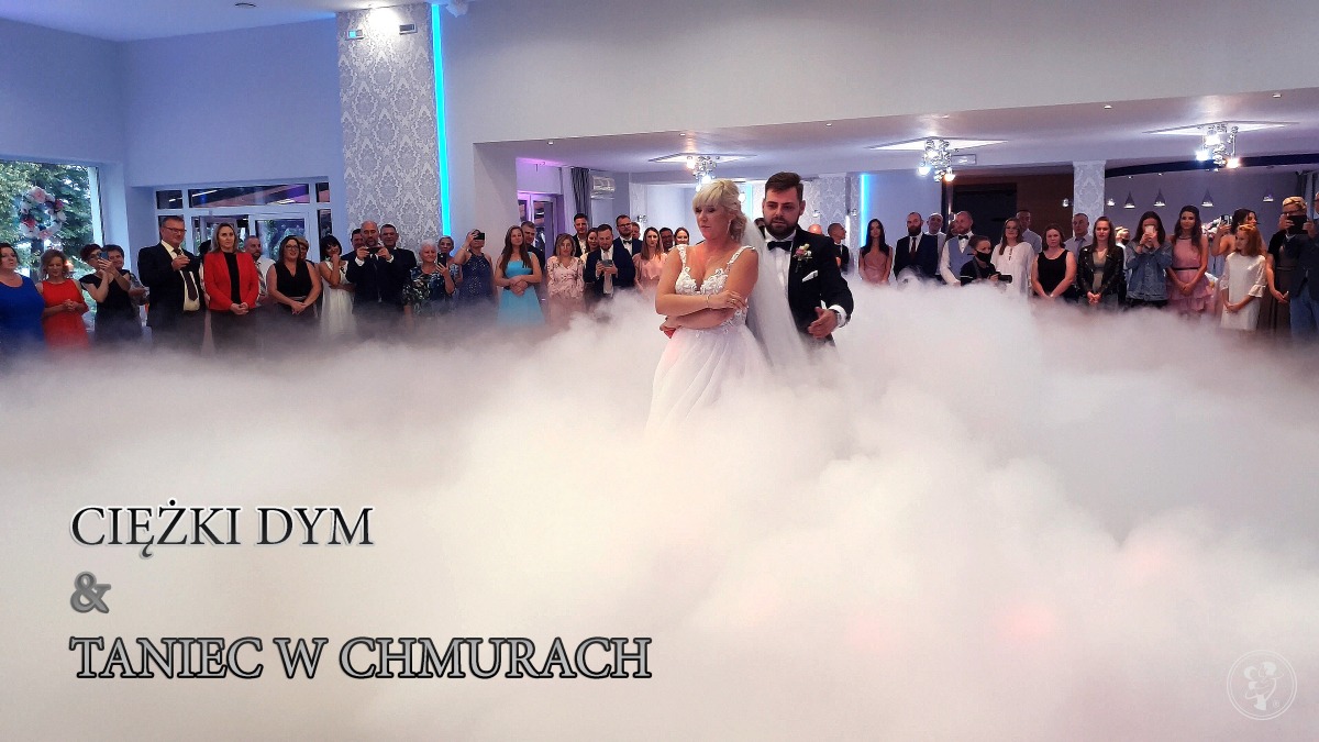 Para młoda podczas pierwszego tańca w chmurach ciężkiego dymu, goście weselni obserwują.