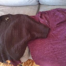 Lidia Szlufik - Dwa swetry damskie leżące na szarej kanapie: luźny, ażurowy kardigan w kolorze ciemnego brązu oraz błyszczący, fioletowy sweter z długim rękawem.