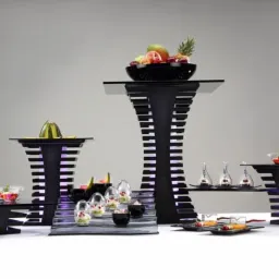 Ekskluzywne, podświetlane ekspozytory na owoce i desery w czarno-białej kolorystyce, ustawione na białym stole na tle szarego tła.