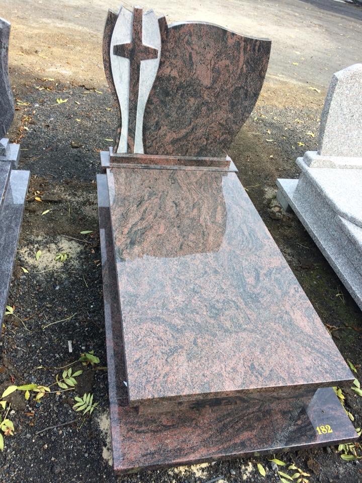 Granitowy nagrobek z krzyżem i ornamentem w kształcie płomienia, wykonany w Międzyrzeczu, z widocznym numerem '182' na podstawie.