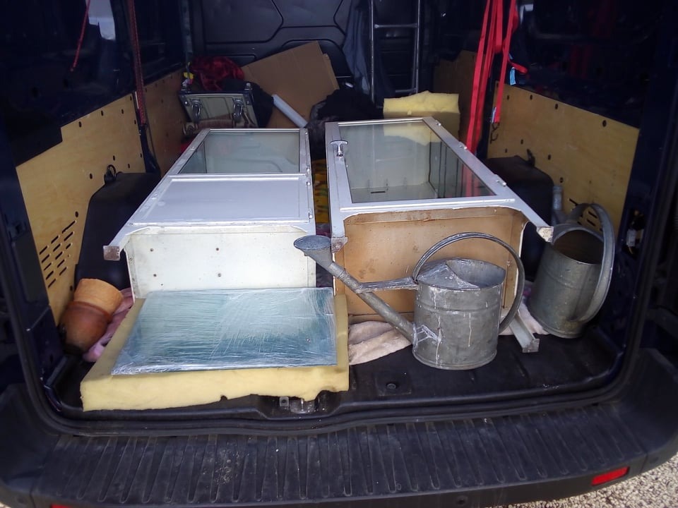 Wnętrze busa z dwoma metalowymi witrynami, szkłem zabezpieczonym folią, pianką, doniczką i dwoma ocynkowanymi konewkami.