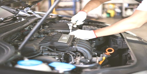 Mechanik w białych rękawicach dokręca śrubę w silniku samochodu Volkswagen za pomocą klucza nasadowego.