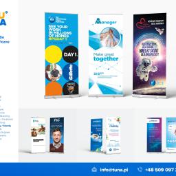 Tuna - studio graficzne - Zestaw roll-upów i ścianek wystawienniczych z różnymi projektami graficznymi, w tym reklamy P&G i inne motywy korporacyjne, prezentowane w jasnym, minimalistycznym studiu.