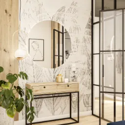 Nowoczesne wnętrze: drewniana konsola z dwoma szufladami pod okrągłym lustrem na tle ściany w liście, monstera w betonowej donicy, wisząca lampa z kulistym kloszem i przeszklone drzwi w czarnej ramie.