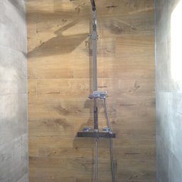 Firma Kornik Michał Modrak - Nowoczesna kabina prysznicowa z deszczownicą i baterią termostatyczną, wykończona płytkami imitującymi drewno i szarym gresem.