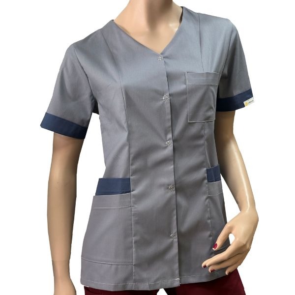 Szary uniform medyczny z granatowymi wstawkami, zapinany na guziki, prezentowany na manekinie. Widoczne kieszenie i krótki rękaw z granatowym mankietem.