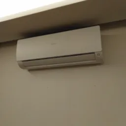 Biała klimatyzacja Haier zamontowana na beżowej ścianie w pomieszczeniu z oświetleniem sufitowym.