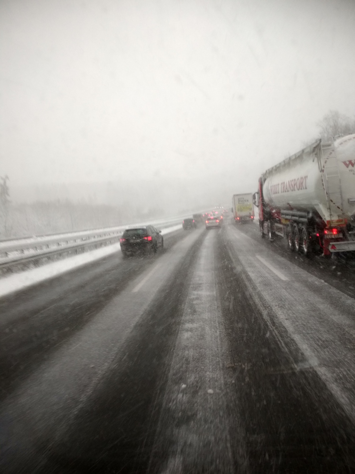 Ciężarówka z cysterną marki Wizet Transport jadąca autostradą w śnieżny dzień, widok z wnętrza pojazdu z perspektywy kierowcy.