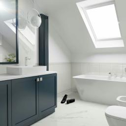 Biostani-architektura - Nowoczesna łazienka na poddaszu z białą armaturą, ciemnogranatową szafką pod umywalką, marmurowymi płytkami i parą czarnych szpilek na podłodze.