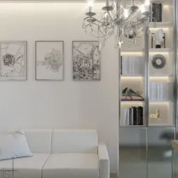 Minimalistyczny salon w jasnych barwach: biała sofa z poduszką, srebrny regał z podświetleniem i dekoracjami, kryształowy żyrandol oraz grafiki z mapami na ścianie.