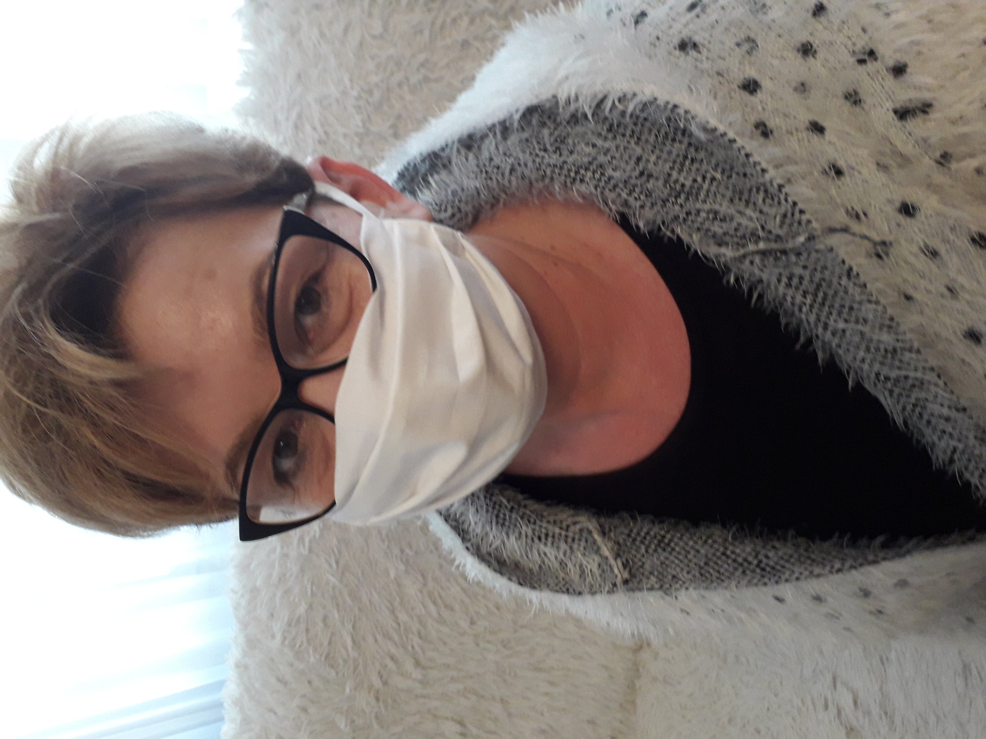 Portret kobiety w okularach i maseczce ochronnej, wykonanej prawdopodobnie w Widawie, z bliska widoczny materiał bluzy.