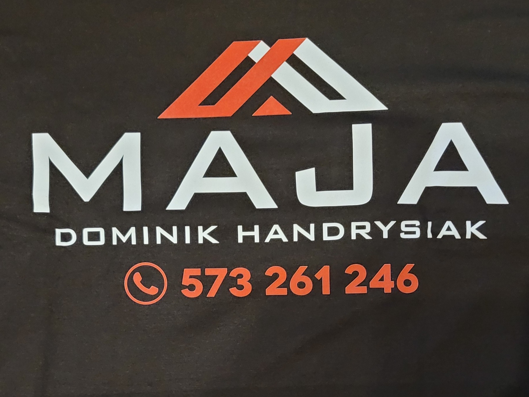 Logo firmy MAJA Dominik Handrysiak z numerem telefonu 573 261 246, pomarańczowo-białe elementy graficzne na ciemnym tle.